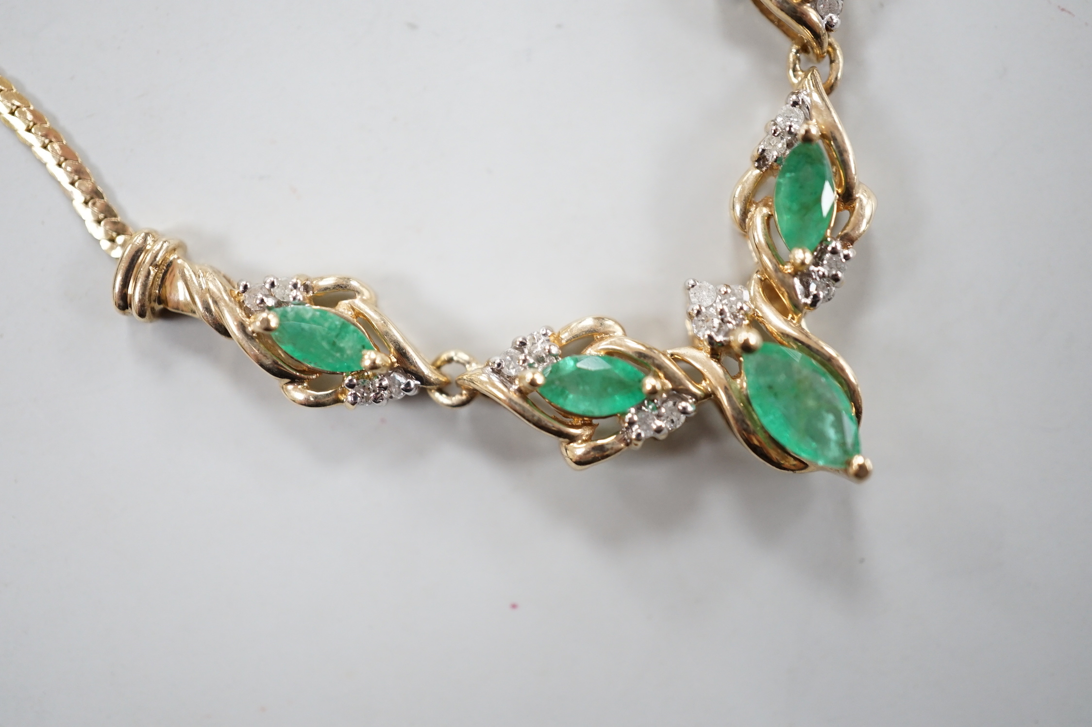 A modern 9ct gold, five stone marquise cut emerald and diamond chip cluster set necklace, 46cm, gross weight 6.2 grams.